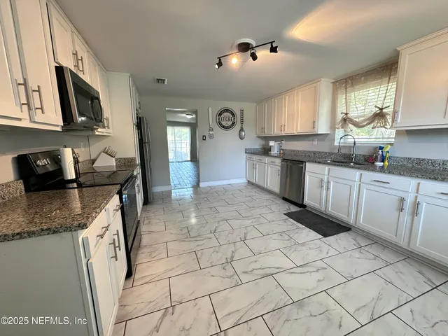 a kitchen with stainless steel appliances granite countertop a sink and a stove