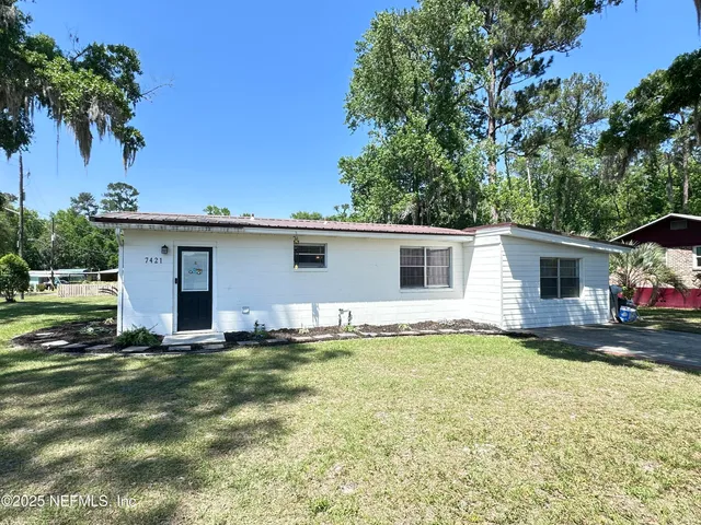 a view of a house with a yard and a large tree