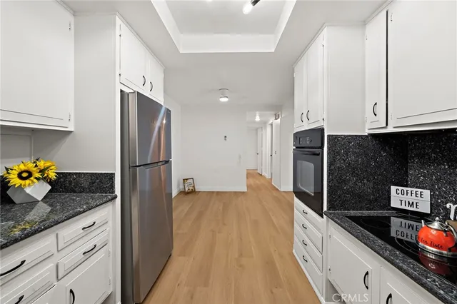 a kitchen with stainless steel appliances granite countertop a stove a sink and a white cabinets