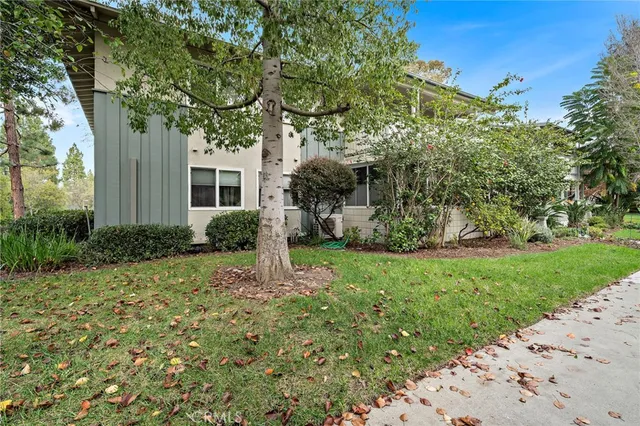 a view of a yard in front of a brick house with large windows