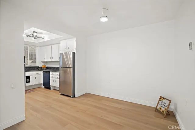 a kitchen with stainless steel appliances a refrigerator a sink and white cabinets