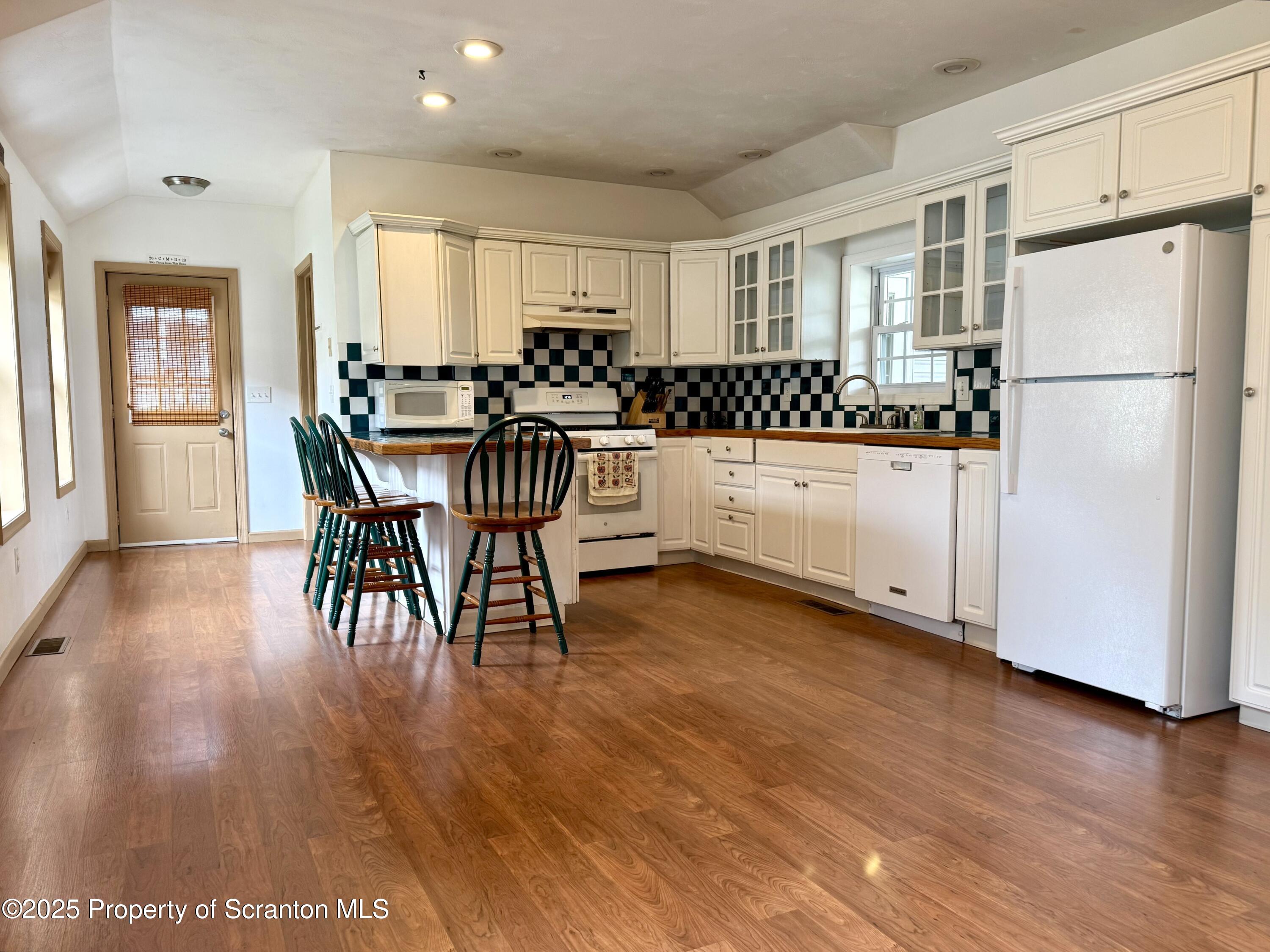 302 Main Street Blakely, PA 18452 - Photo 22 of 38 a kitchen with stainless steel appliances granite countertop a refrigerator a stove a sink a dining table and chairs with wooden floor
