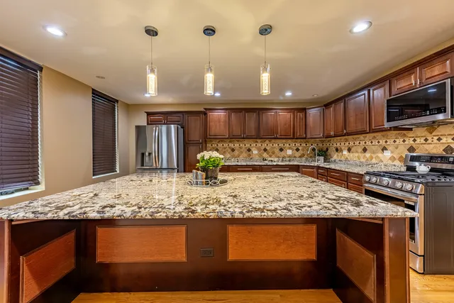 a kitchen with stainless steel appliances granite countertop wooden cabinets and a counter top space