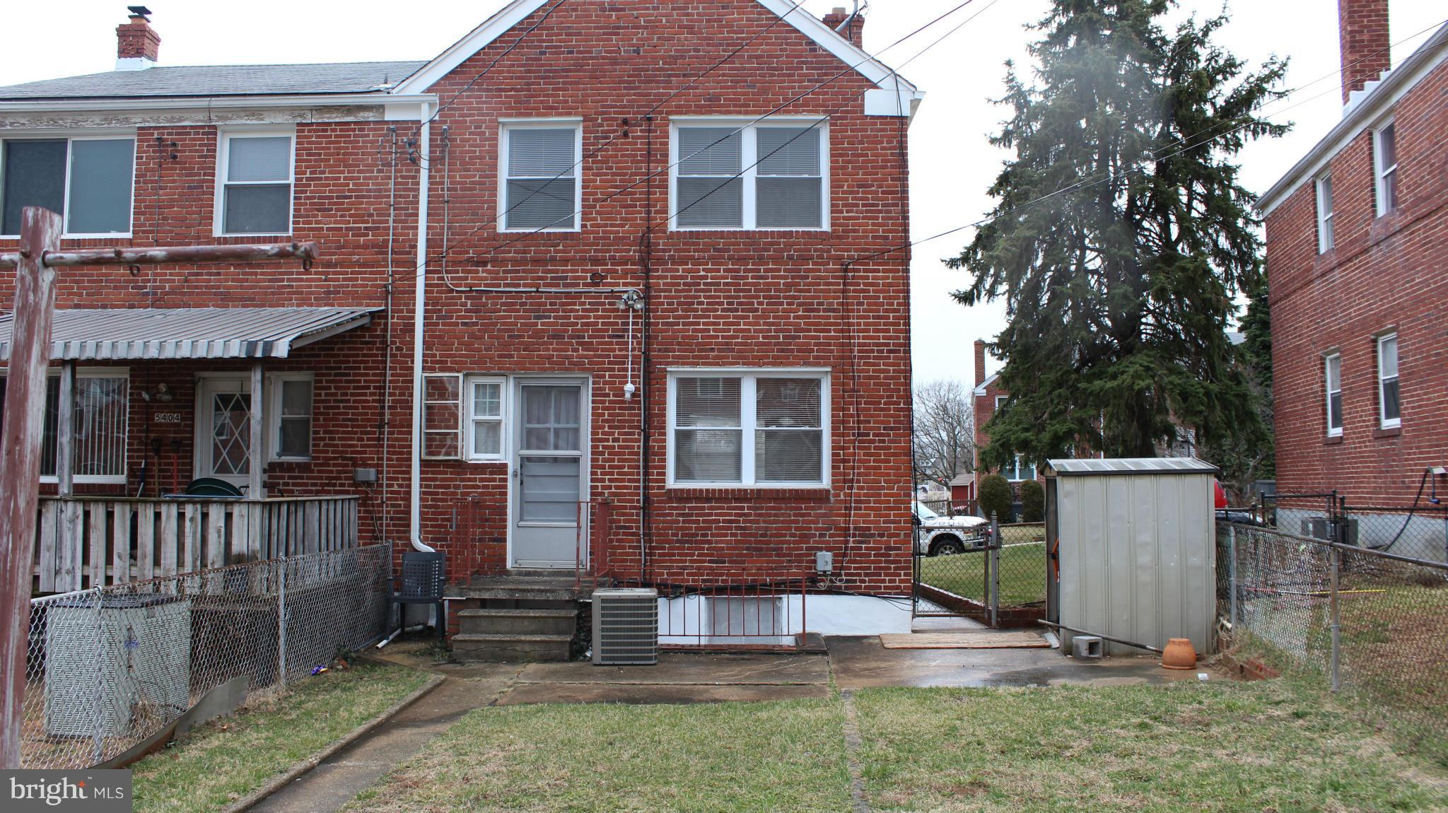 5406 Whitlock Road Baltimore, MD 21229 - Photo 22 of 25 a view of a brick house with many windows and a yard