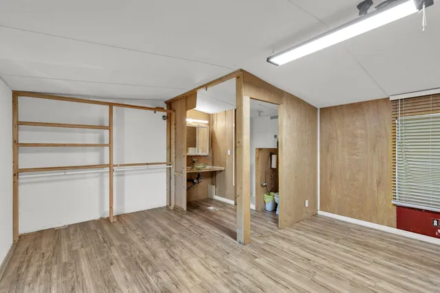 a view of an empty room with window and wooden floor