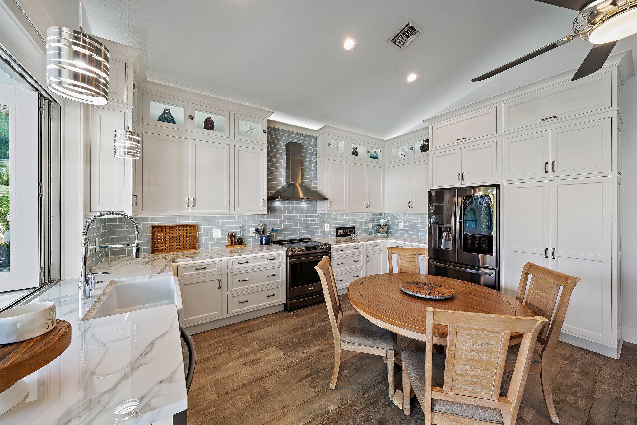 3443 Inlet Court Jupiter, FL 33469 - Photo 24 of 59 a kitchen with stainless steel appliances kitchen island granite countertop a dining table chairs and a refrigerator