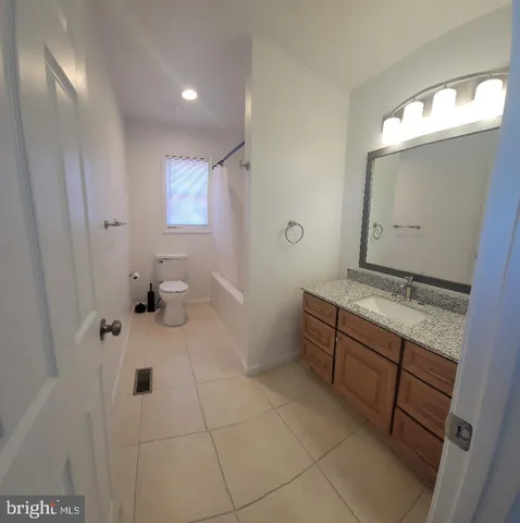 a spacious bathroom with a granite countertop sink a toilet and mirror