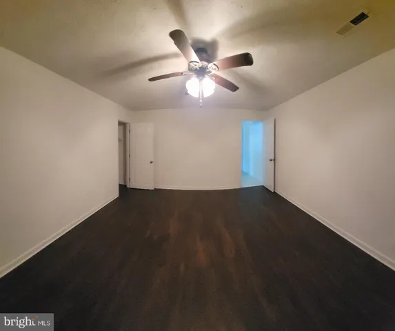 a view of an empty room with a ceiling fan and window