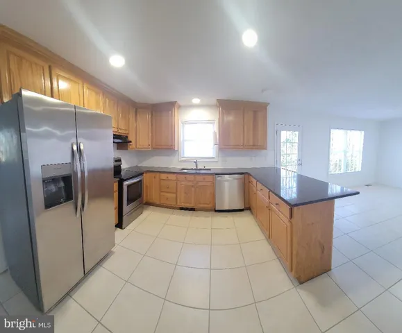 a large kitchen with stainless steel appliances granite countertop a refrigerator and a sink