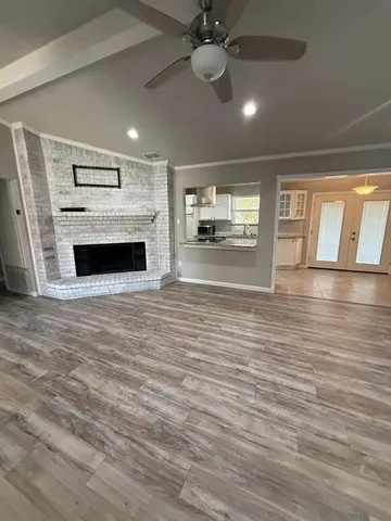 a view of a livingroom with a fireplace a ceiling fan and wooden floor