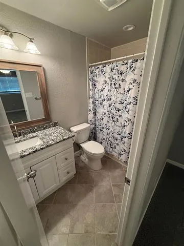 a bathroom with a granite countertop sink a toilet and a mirror