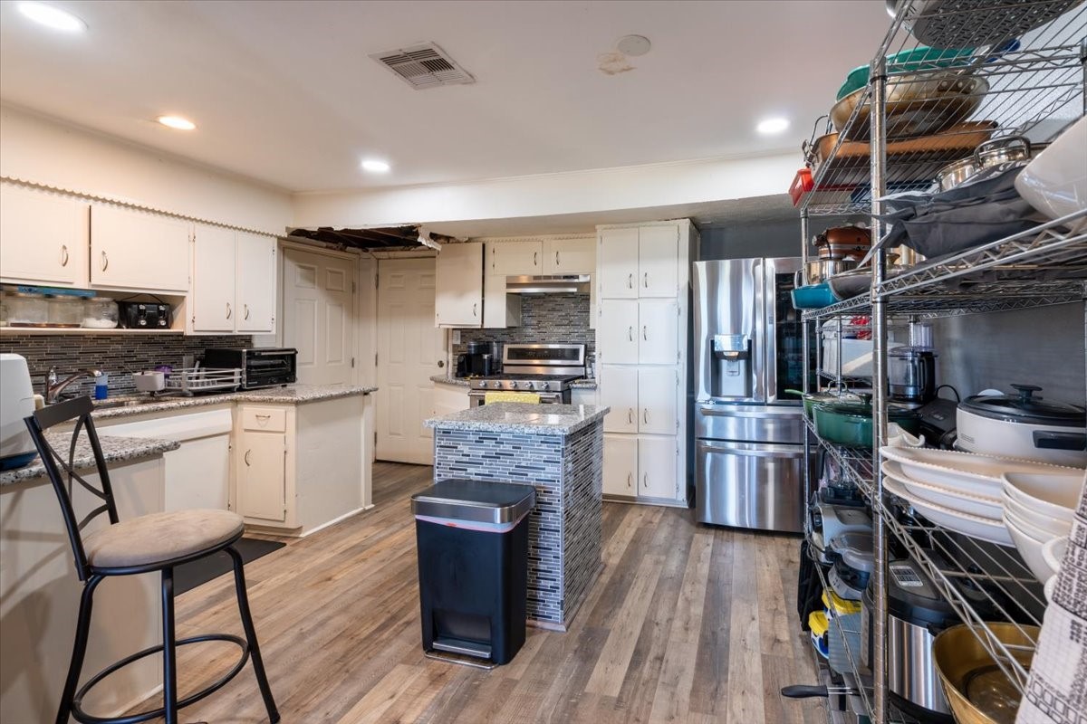10601 Buffum Street Houston, TX 77051 - Photo 9 of 50 a kitchen with stainless steel appliances kitchen island granite countertop a refrigerator oven a stove a sink a dining table and chairs with wooden floor