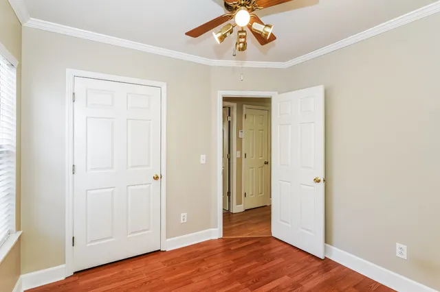 an empty room with wooden floor and ceiling fan