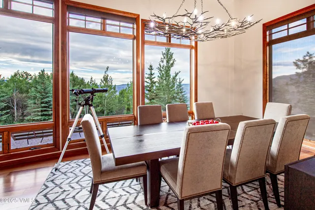 a dining room with wooden floor a chandelier a glass table and chairs