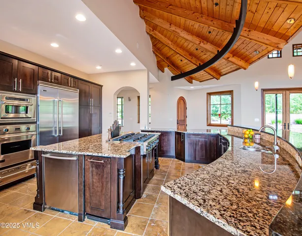 a large kitchen with stainless steel appliances granite countertop a stove a sink and a refrigerator