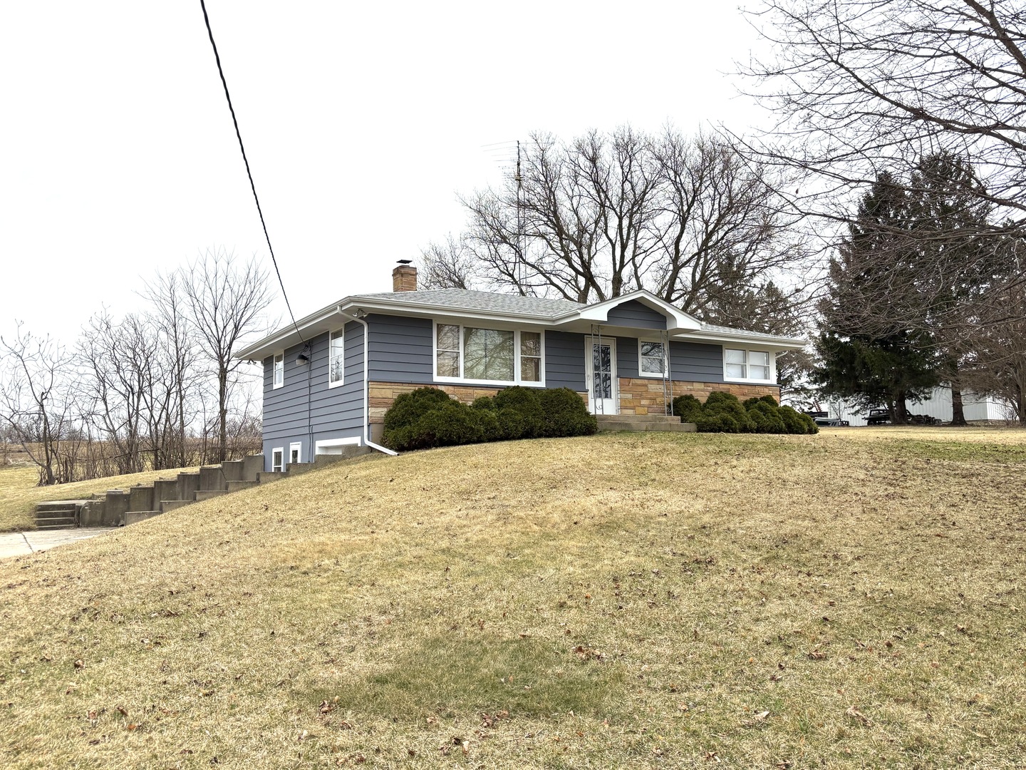 2208 Stieg Road Woodstock, IL 60098 - Photo 1 of 15 a front view of a house with a yard covered with snow and buildings