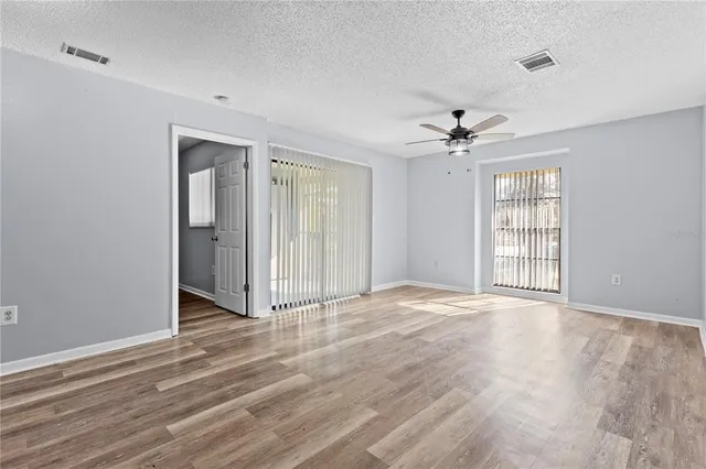 a view of an empty room with window and wooden floor