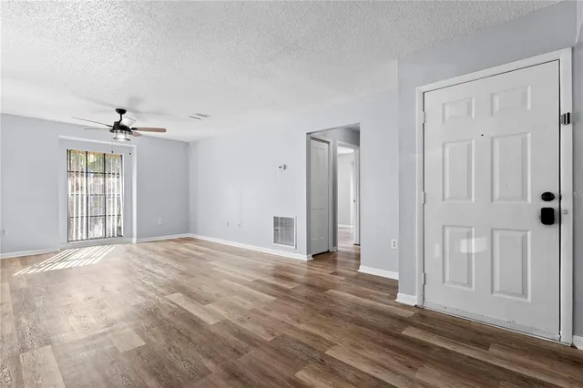 a view of an empty room with wooden floor and a window