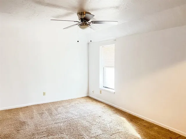 an empty room with a ceiling fan and a window