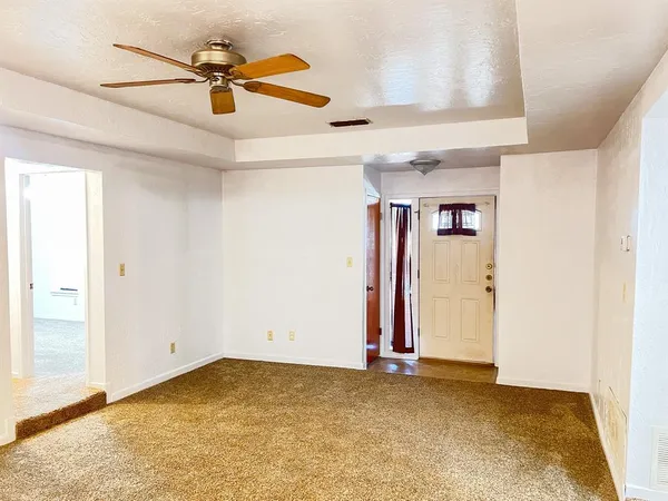 an empty room with ceiling fan and window