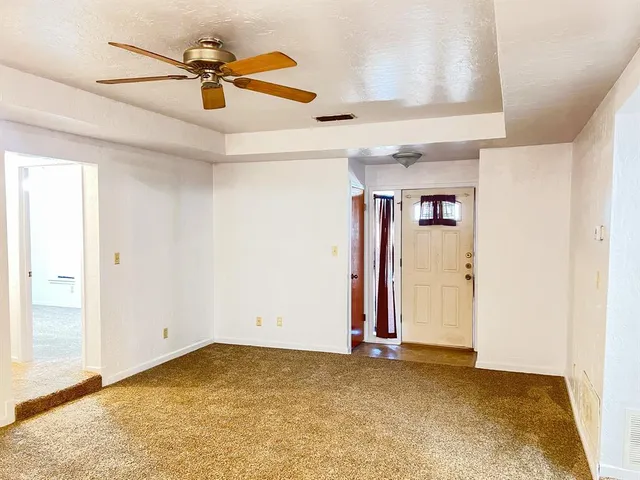 an empty room with ceiling fan and window