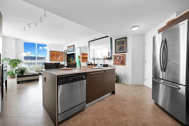 a kitchen with stainless steel appliances kitchen island granite countertop a table chairs and a refrigerator