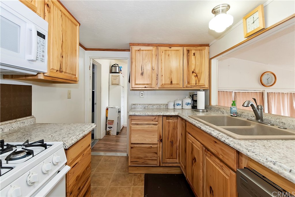 1211 Bridal Path Rimforest, CA 92378 - Photo 16 of 28 a kitchen with granite countertop a sink stove and refrigerator