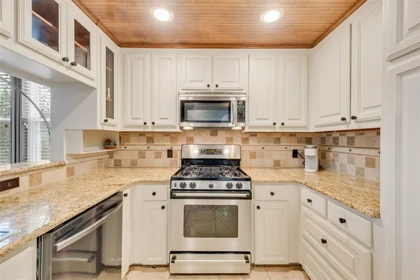 a kitchen with granite countertop white cabinets and white appliances