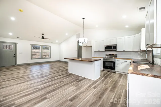 an empty room with wooden floor a ceiling fan and windows