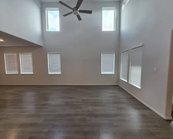 a view of an empty room with wooden floor and window