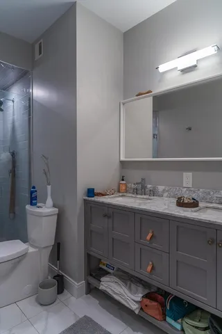 a bathroom with a toilet a sink a glass door a shower and a mirror