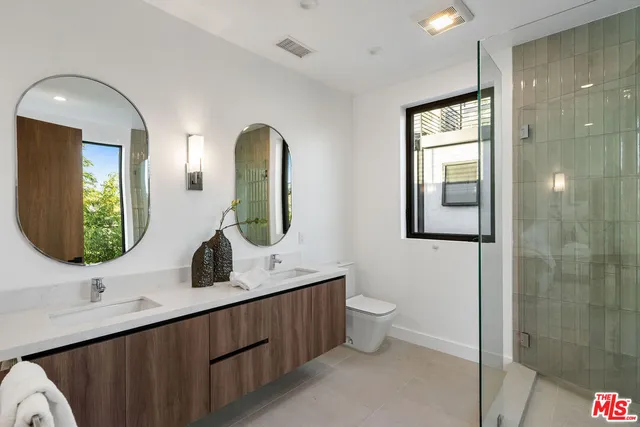 a bathroom with a double vanity sink toilet and mirror