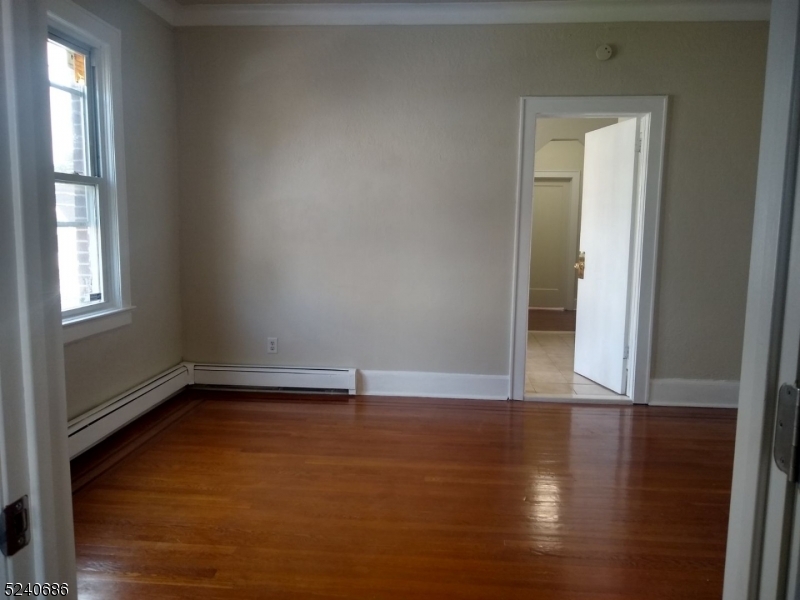 326 Field Place, Unit 2L Hillside, NJ 07205 - Photo 15 of 17 an empty room with wooden floor and windows