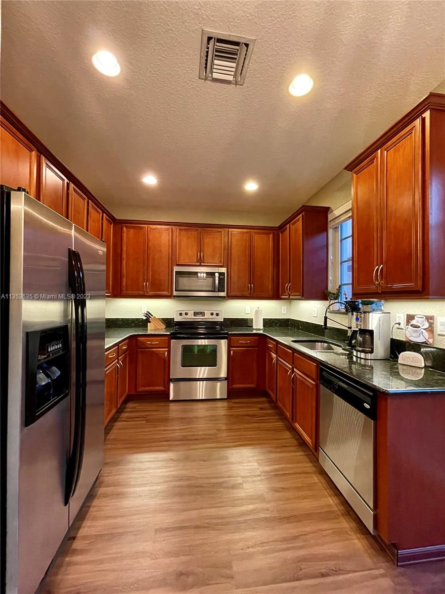 128 Midleton Way Jupiter, FL 33458 - Photo 14 of 39 a large kitchen with stainless steel appliances wooden cabinets a stove and a refrigerator
