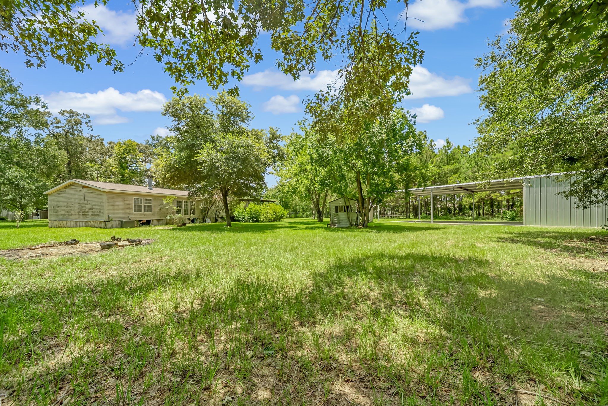 25979 Shade Tree Lane Splendora, TX 77372 - Photo 5 of 22 Enjoy a well-designed layout with the manufactured home, storage shed, and expansive metal building, each offering its own dedicated space while preserving the property's open feel and versatility.