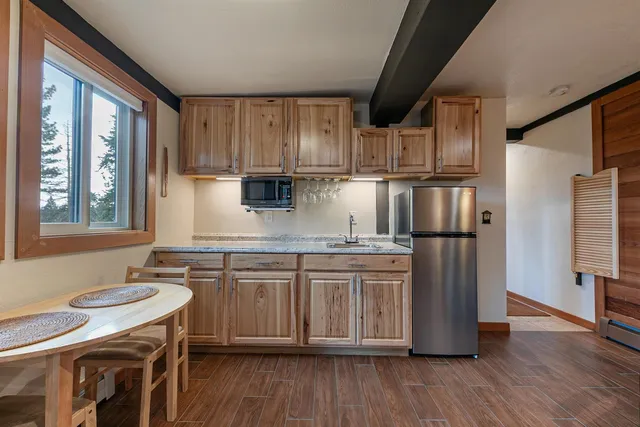 a kitchen with stainless steel appliances granite countertop a refrigerator a sink dishwasher a stove and white countertops with wooden floor