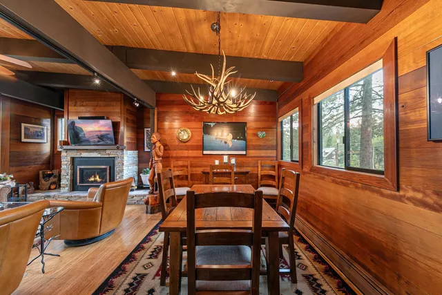 a view of a dining room with furniture a chandelier and large windows