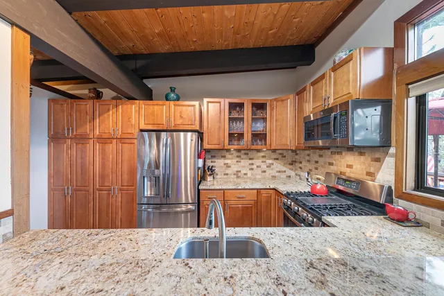a kitchen with stainless steel appliances kitchen island granite countertop a refrigerator and a sink