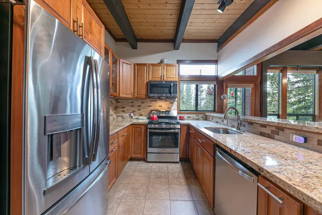 a large kitchen with stainless steel appliances granite countertop a stove and a sink