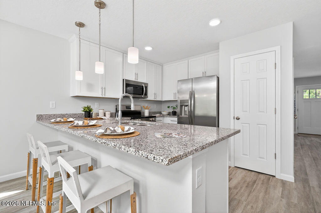 857 Jackson Road Jacksonville, FL 32225 - Photo 8 of 29 a kitchen with stainless steel appliances granite countertop a sink a stove a refrigerator and island with wooden floor
