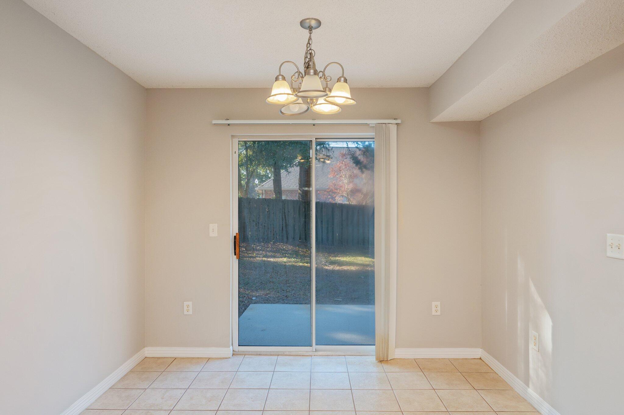 546 Tikell Drive Crestview, FL 32536 - Photo 8 of 20 an empty room with windows and chandelier