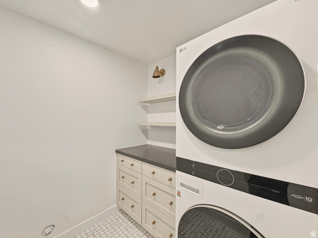 870 North Ada Loop Lehi, UT 84048 - Photo 40 of 51 Laundry room featuring stacked front-load appliances, a built-in cabinet with a dark countertop, open shelving, a wall-mounted light fixture, and recessed lighting