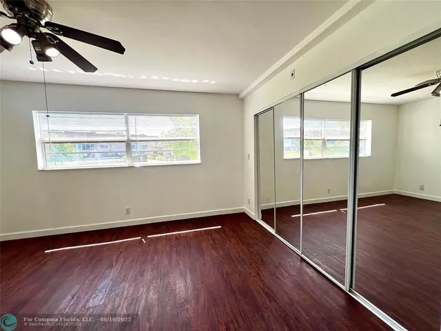 a view of empty room with wooden floor and fan