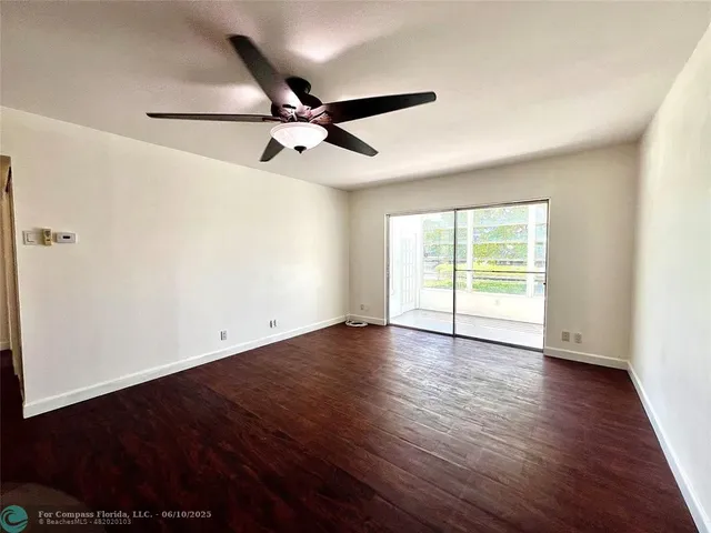 an empty room with wooden floor fan and windows