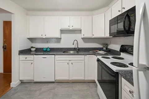 a kitchen with granite countertop white cabinets stainless steel appliances and a sink