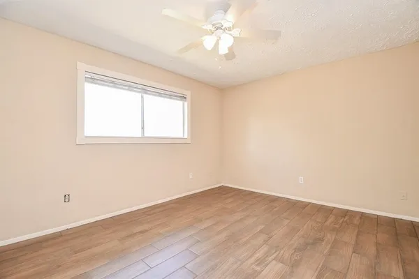 an empty room with a window and a ceiling fan