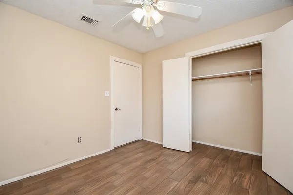 an empty room with wooden floor and a ceiling fan