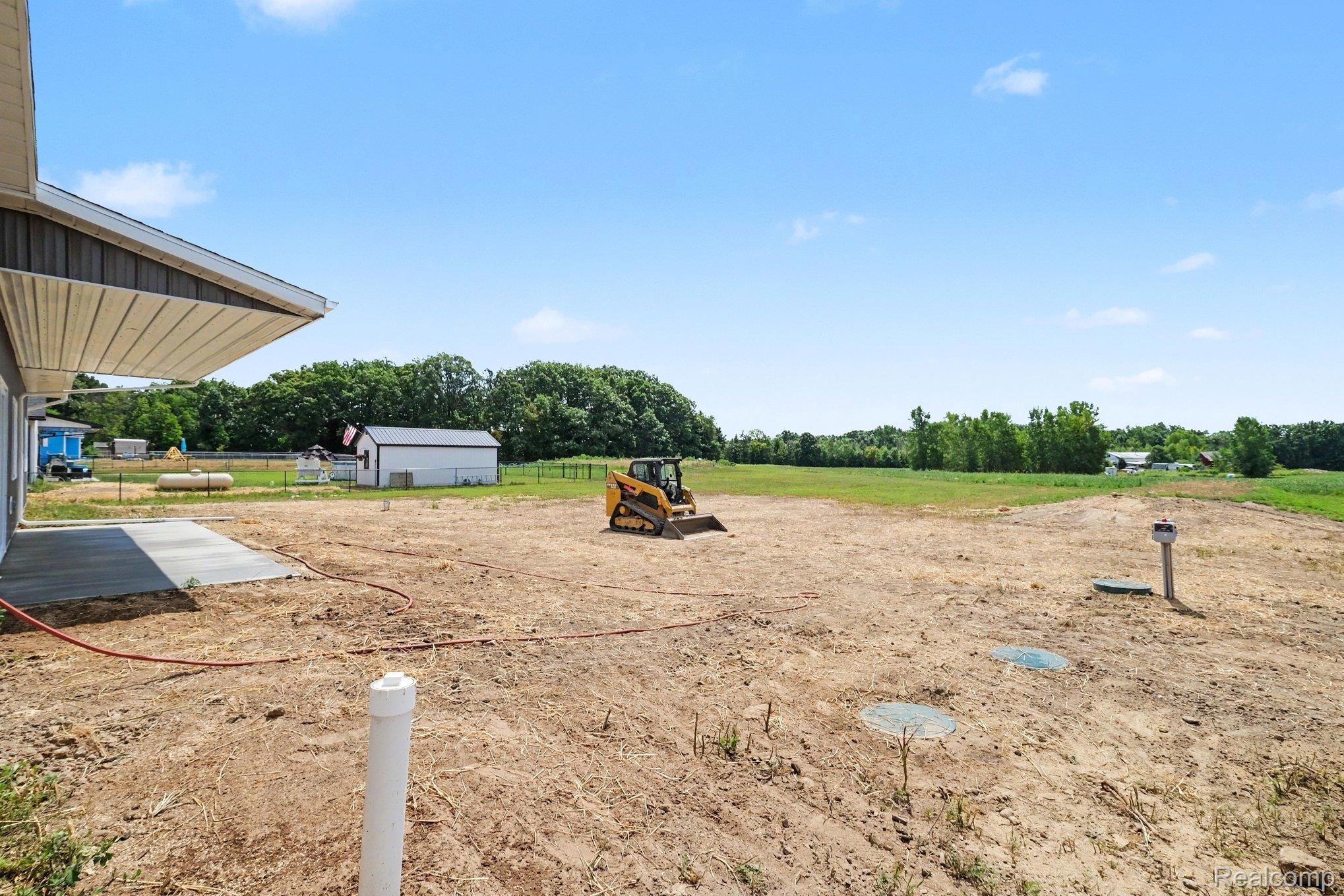 12425 Miller Road Lennon, MI 48449 - Photo 23 of 26 Spacious unimproved land offering a large flat area, partial concrete pad, and a separate storage shed