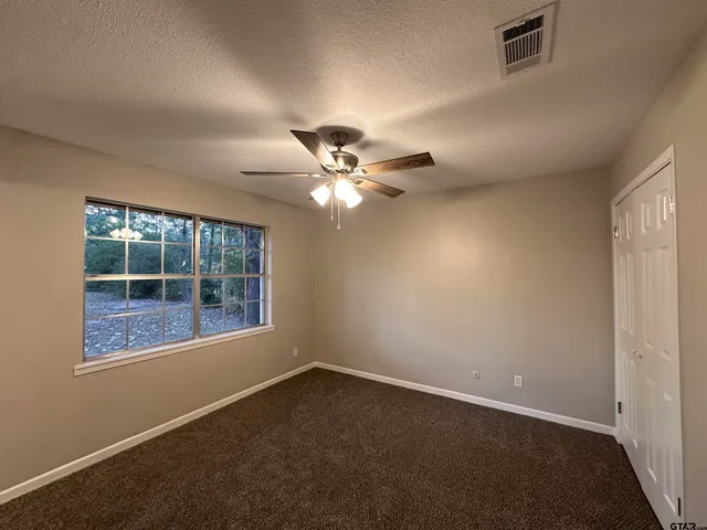 an empty room with a window and a fan