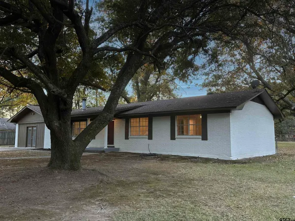 a front view of a house with large trees